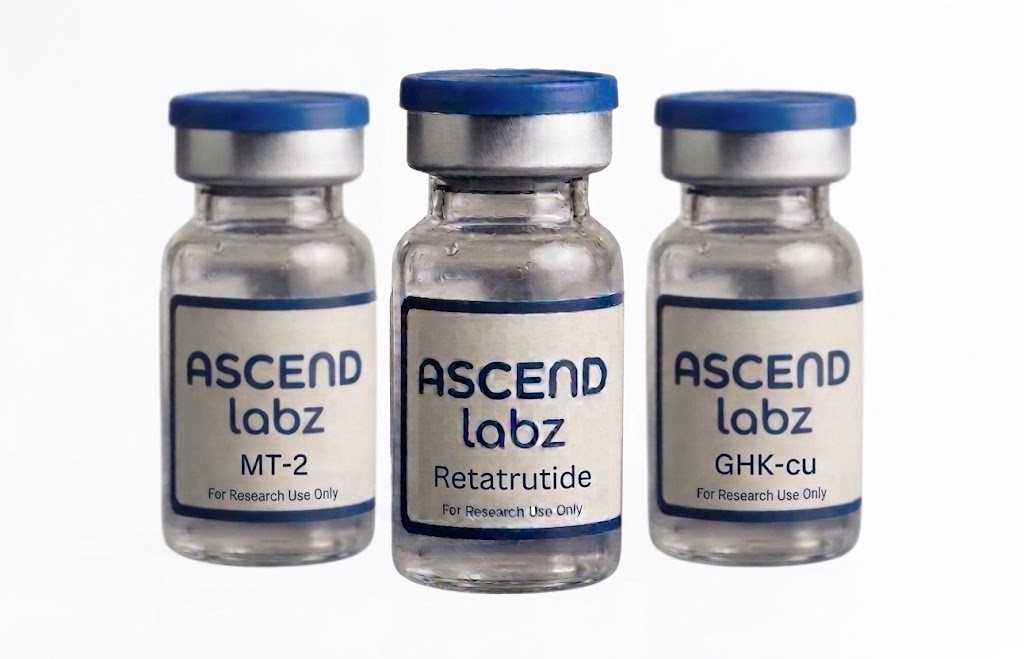 Three small clear glass vials with blue caps and white labels reading ASCEND labz, arranged side by side on a white background. The center vial label reads Retatrutide, and the side vials read MT-2 and GHK-cu.