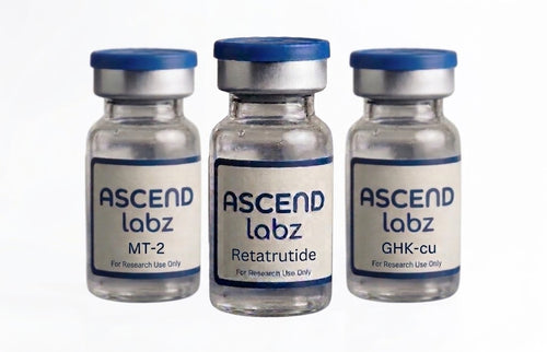 Three small clear glass vials with blue caps and white labels reading ASCEND labz, arranged side by side on a white background. The center vial label reads Retatrutide, and the side vials read MT-2 and GHK-cu.